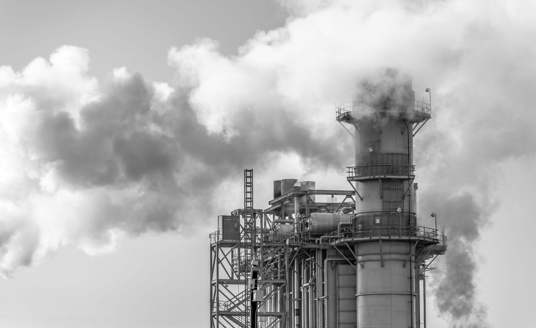 Industriële installatie met hoge schoorsteen en dikke wolken